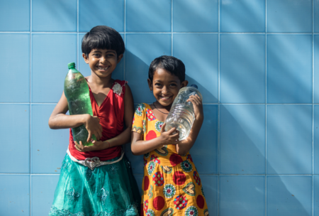 two young girls standing holding bottles of water