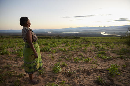 Florine, 55, walking by the edge of the village, waiting for somebody to return from the water source who will be willing to sell her water, Manintsevo village, Berano Ville commune, Amboasary District, Anosy Region, Madagascar, June 2022.