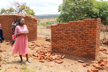 Esther Pondani, Facility In-charge at Chandawe Health Centre, showcasing toilets built by the community.