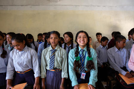 En skolklass i skoluniform men en leende flicka i mitten.