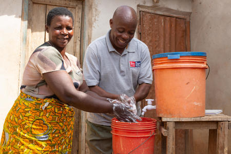 Mashlari John Shirima, 59, trainer of trainers, teaching Lucia Godfrey, 55, how to wash her hands with soap, Chikobe village, Geita District, Tanzania, June, 2019.