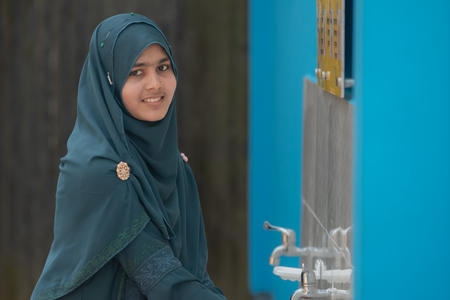 Hawa washing her hands with clean water at a new WASH block at her Madrassa.