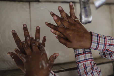 School children wash the tops of their hands at a handwashing station at South Delhi Nigam Primary School