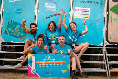 WaterAid volunteers outside the Good Loos at the end of the festival with the totaliser showing how many toilets have been funded to be built in Rwanda. Bestival, Dorset, UK, August 2018