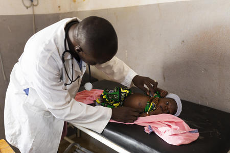 Dr Martin assesses three-month-old baby Drissa, who is suffering with skin abscesses caused by a lack of  hygiene, at Talo Health Centre, Mali