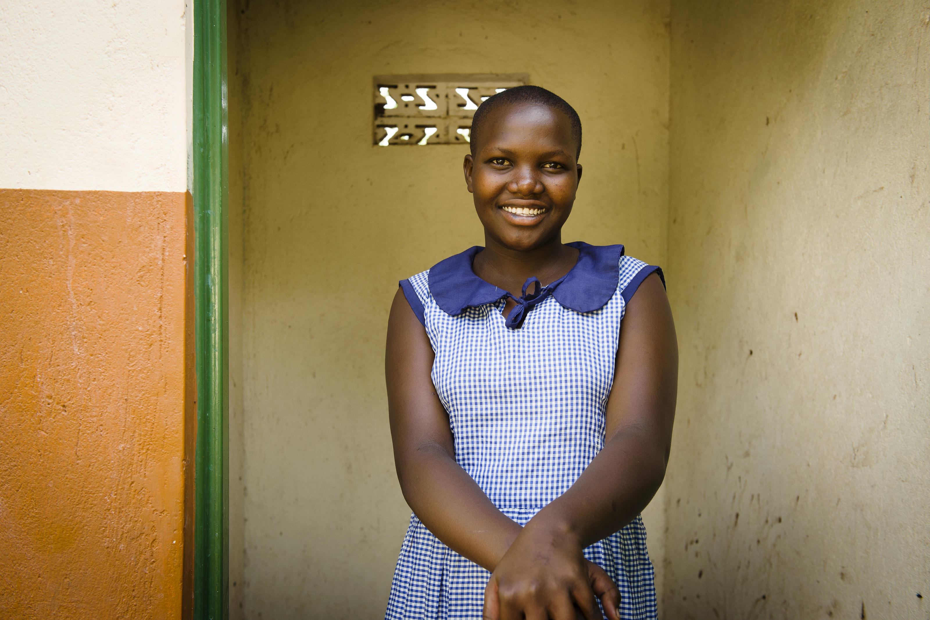 Sharon, WASH Club member, stands outside the newly built WaterAid latrine block at St Mary's School in Uganda.