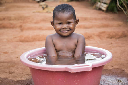 Fitahiana, 3 years old, enjoying a bucket bath with clean water outside her house in Ambohibary village, Tsiroanomandidy district, Madagascar, December 2017.